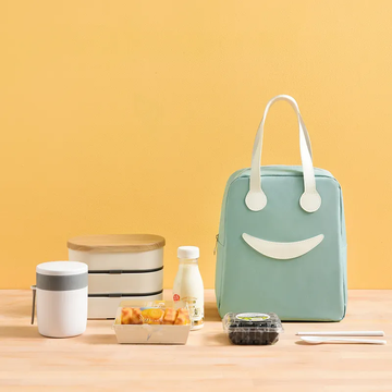 Green lunch bag with smiley face design on a yellow background